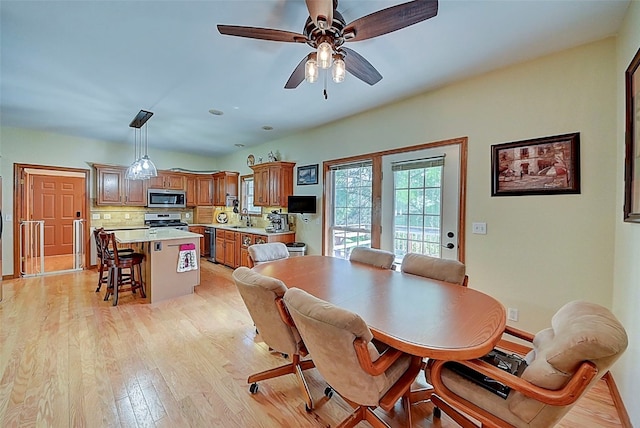 dining room with ceiling fan, baseboards, and light wood-style flooring