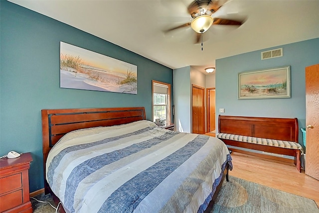 bedroom featuring visible vents, a closet, wood finished floors, and a ceiling fan