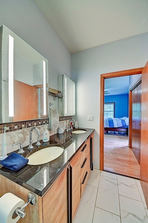 full bathroom with double vanity, marble finish floor, ensuite bath, and a sink