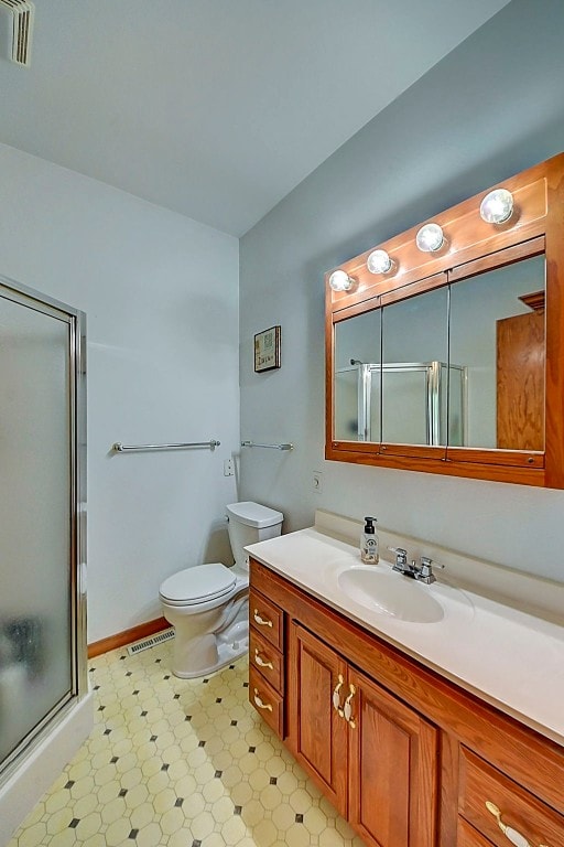 bathroom featuring vanity, a shower stall, toilet, and visible vents