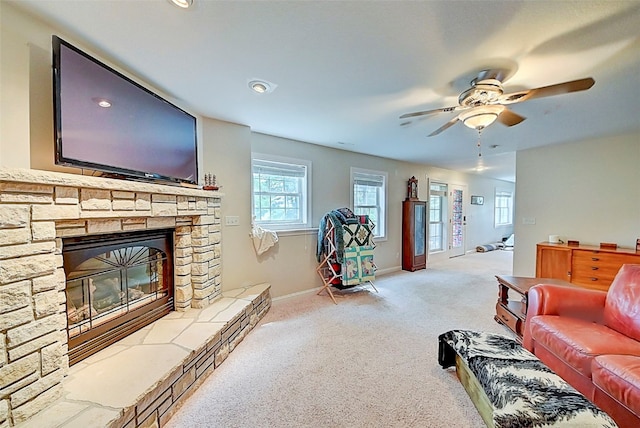 living room featuring baseboards, light carpet, ceiling fan, and a fireplace