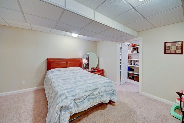 carpeted bedroom with a paneled ceiling and baseboards