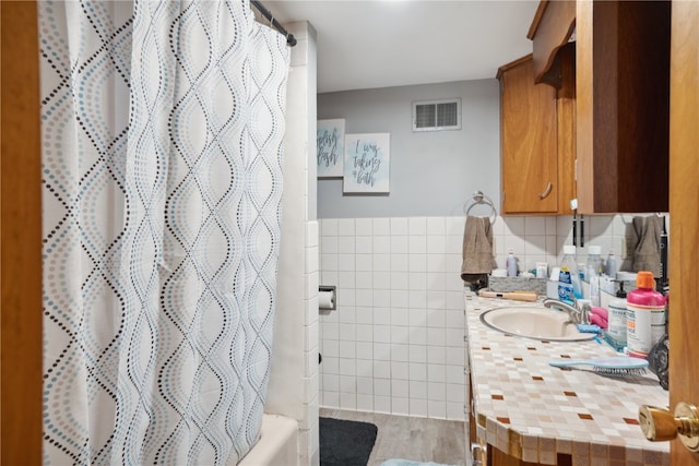 bathroom featuring backsplash, vanity, tile walls, hardwood / wood-style flooring, and shower / bath combination with curtain