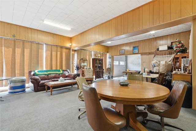 dining space with wood walls and carpet flooring