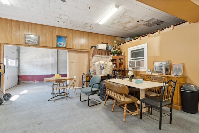 dining room featuring wood walls and carpet flooring