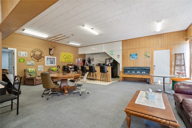 carpeted dining space with wood walls