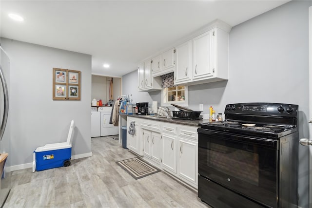 kitchen with light wood-type flooring, electric range, separate washer and dryer, white cabinets, and sink