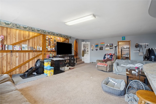 carpeted living room featuring wood walls