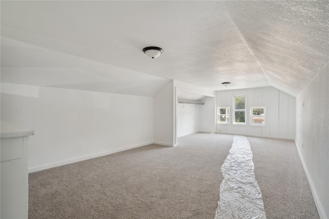 bonus room with light colored carpet, a textured ceiling, and lofted ceiling