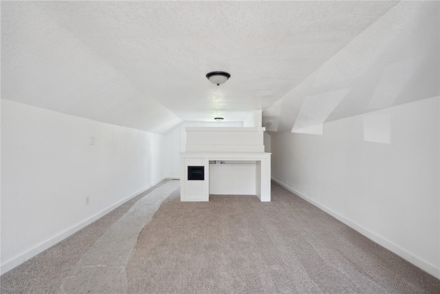 bonus room featuring a textured ceiling, lofted ceiling, and light colored carpet