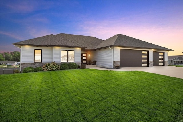 prairie-style home with a garage, a front yard, stone siding, and driveway