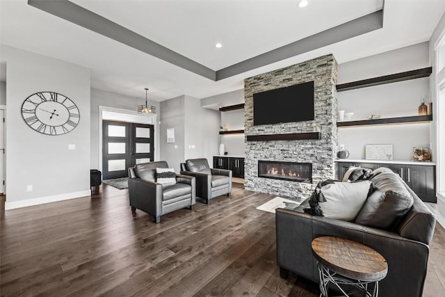 living room with dark wood-style floors, a fireplace, recessed lighting, a raised ceiling, and baseboards