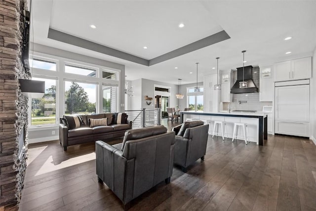 living area featuring baseboards, a tray ceiling, dark wood-type flooring, and recessed lighting