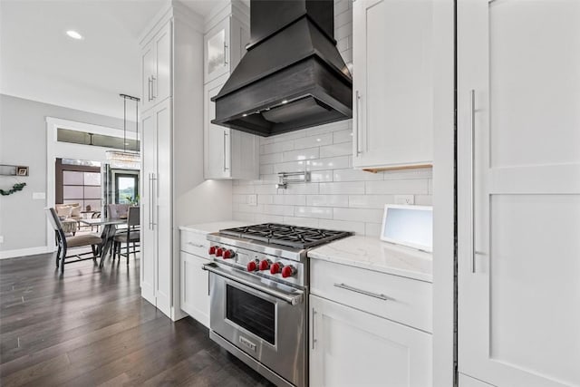 kitchen with custom range hood, backsplash, white cabinets, premium range, and light stone countertops