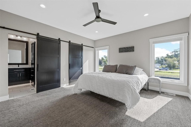 bedroom with a barn door, multiple windows, and light colored carpet