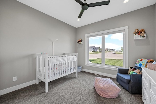 bedroom with carpet floors, ceiling fan, a crib, and baseboards