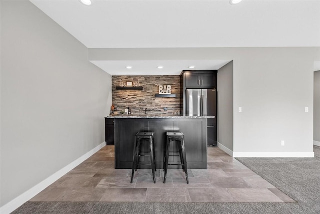 bar with wet bar, freestanding refrigerator, and baseboards