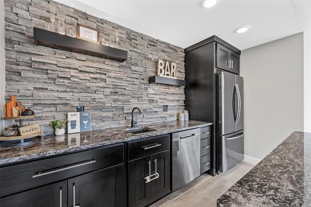 kitchen with open shelves, stainless steel appliances, a sink, dark stone countertops, and dark cabinets