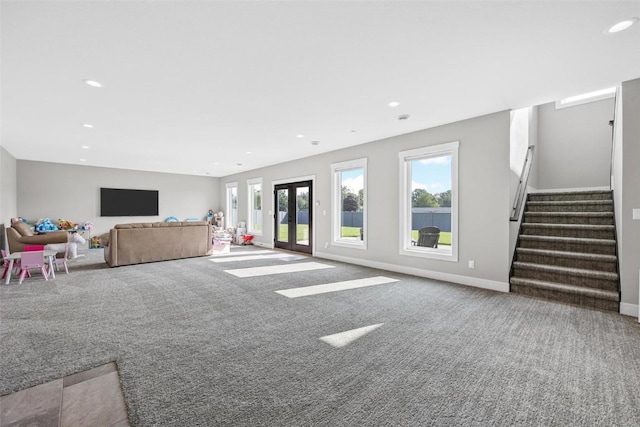 unfurnished living room featuring carpet floors, baseboards, stairway, and french doors