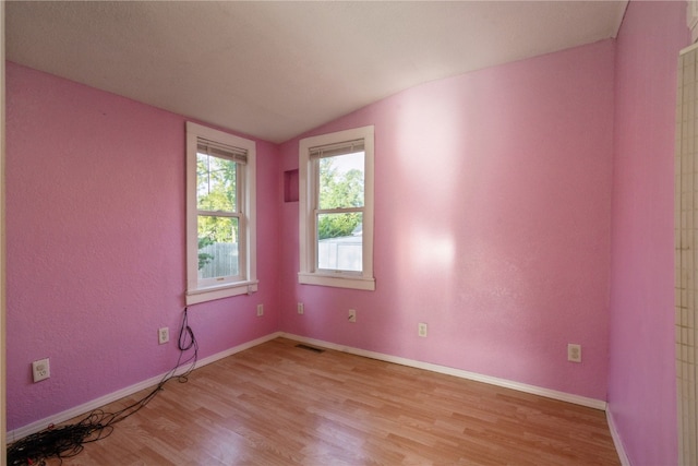 empty room with vaulted ceiling and light hardwood / wood-style floors