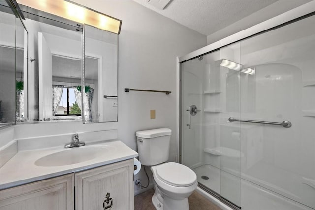 full bath featuring a stall shower, vanity, toilet, and a textured ceiling