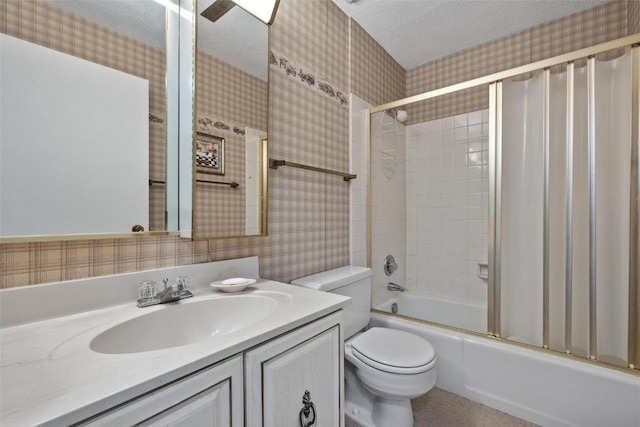 full bath featuring wallpapered walls, toilet, combined bath / shower with glass door, a textured ceiling, and vanity