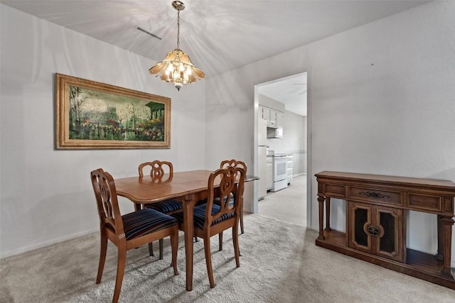 dining space with carpet and a notable chandelier