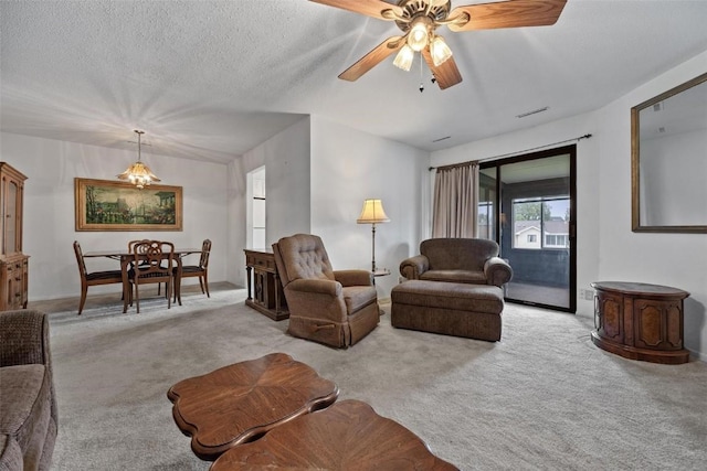 living area with light carpet, ceiling fan, and a textured ceiling