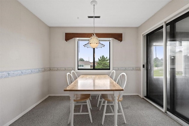 unfurnished dining area with carpet floors, a wainscoted wall, and visible vents