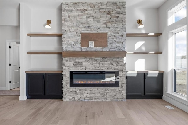 unfurnished living room featuring a healthy amount of sunlight, a fireplace, and light hardwood / wood-style flooring