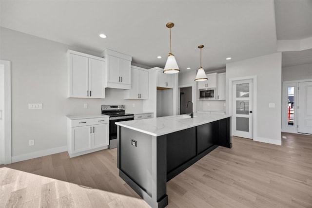 kitchen featuring decorative light fixtures, white cabinetry, stainless steel appliances, a kitchen island with sink, and light stone counters