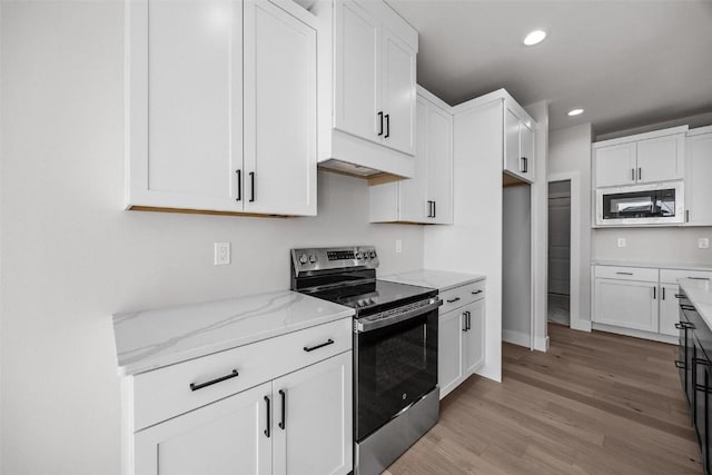 kitchen with light stone countertops, white cabinetry, light hardwood / wood-style floors, stainless steel range with electric stovetop, and built in microwave