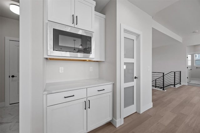 kitchen featuring light wood-type flooring, built in microwave, and white cabinetry