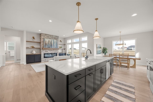 kitchen with light countertops, light wood-type flooring, plenty of natural light, and a sink