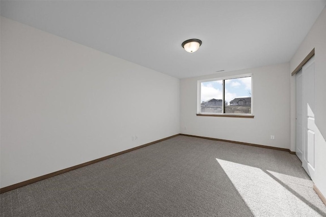 empty room featuring carpet and baseboards