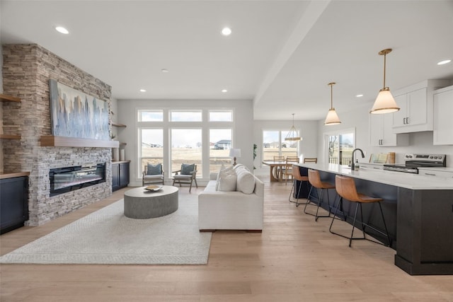 living room featuring recessed lighting, a stone fireplace, and light wood-type flooring