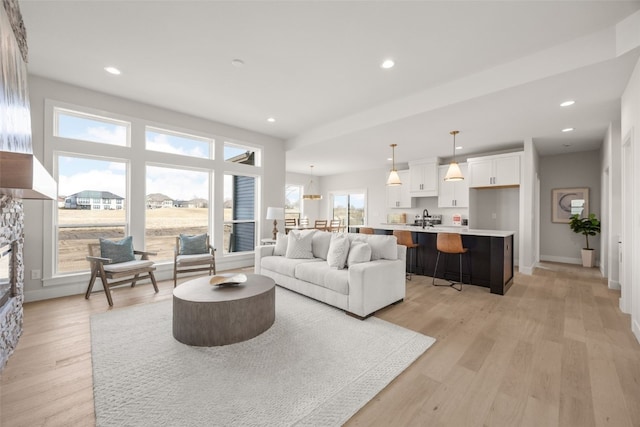 living room featuring light wood finished floors, recessed lighting, and baseboards