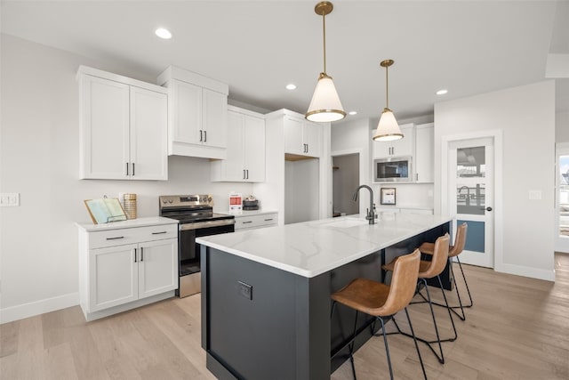 kitchen featuring a sink, baseboards, stainless steel appliances, and light wood-type flooring