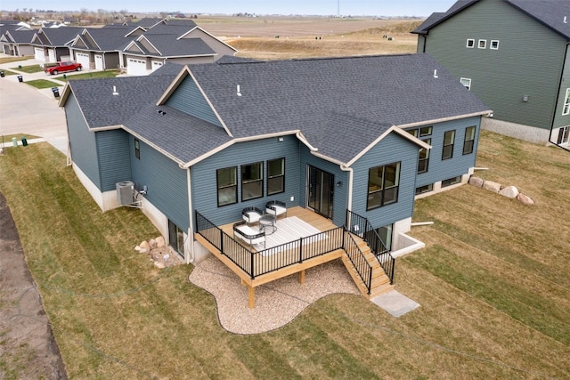 rear view of house featuring a shingled roof, a residential view, cooling unit, a lawn, and a deck