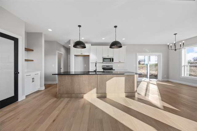 kitchen featuring white cabinets, appliances with stainless steel finishes, light hardwood / wood-style floors, and a large island with sink