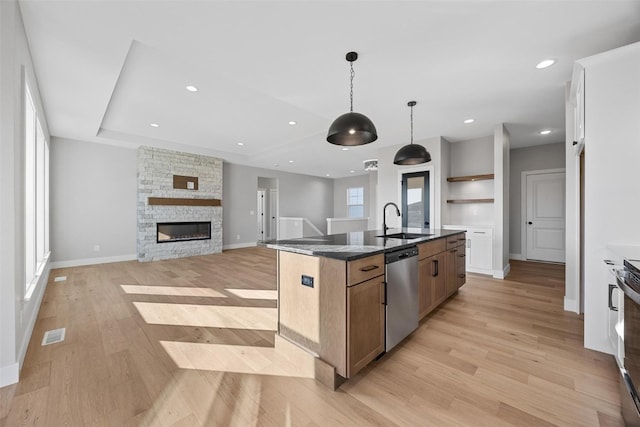 kitchen featuring a center island with sink, dishwasher, a healthy amount of sunlight, and decorative light fixtures