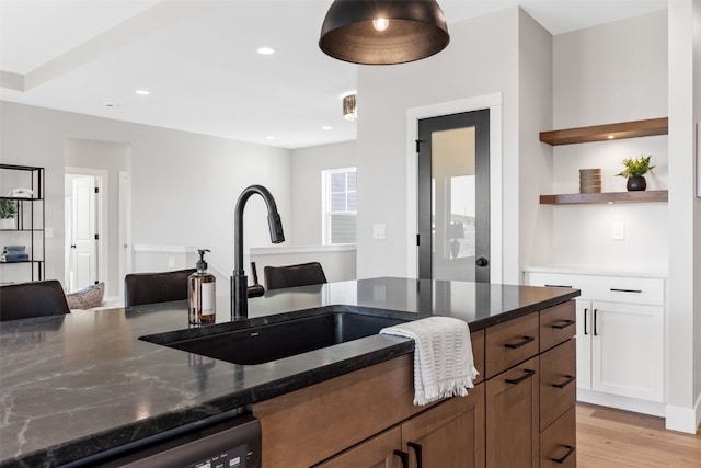 1510 Cardinal Dr, Fairfax, IA 52228 - kitchen featuring a sink, dishwashing machine, dark stone countertops, open shelves, and light wood finished floors