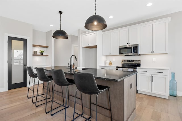 1510 Cardinal Dr, Fairfax, IA 52228 - kitchen with stainless steel appliances, light wood-style flooring, white cabinets, a kitchen island with sink, and recessed lighting