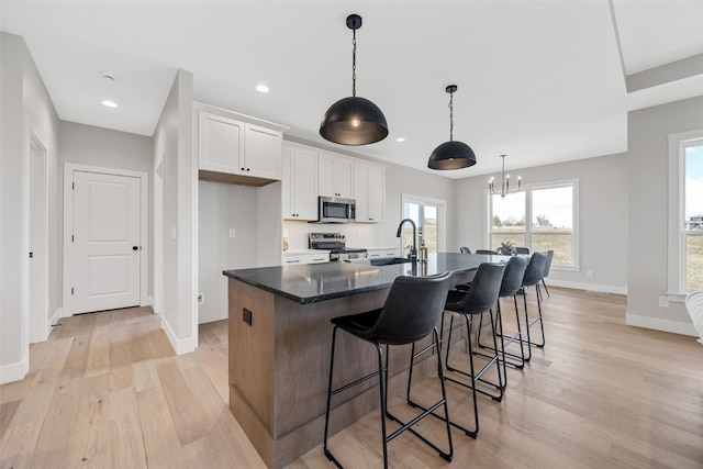 1510 Cardinal Dr, Fairfax, IA 52228 - kitchen with stainless steel appliances, a sink, light wood-style flooring, baseboards, and white cabinets