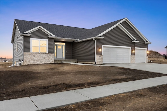 view of front of property with stone siding, roof with shingles, an attached garage, and concrete driveway