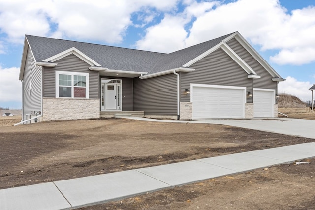 view of front facade with an attached garage, stone siding, driveway, and roof with shingles