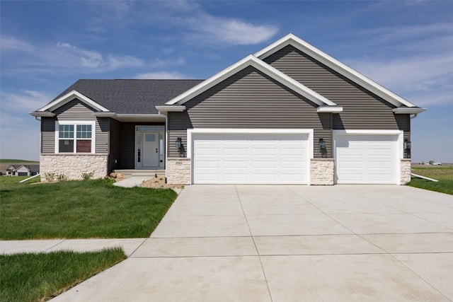1519 Cardinal Dr, Fairfax, IA 52228 - view of front of home featuring stone siding, concrete driveway, a garage, and a front lawn