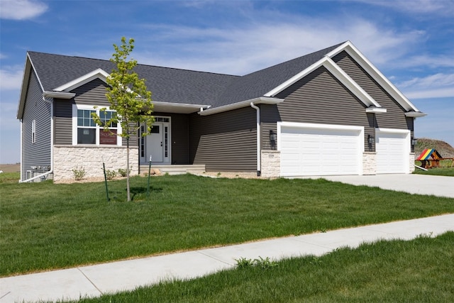 1519 Cardinal Dr, Fairfax, IA 52228 - view of front of home with stone siding, an attached garage, a front yard, driveway, and a shingled roof