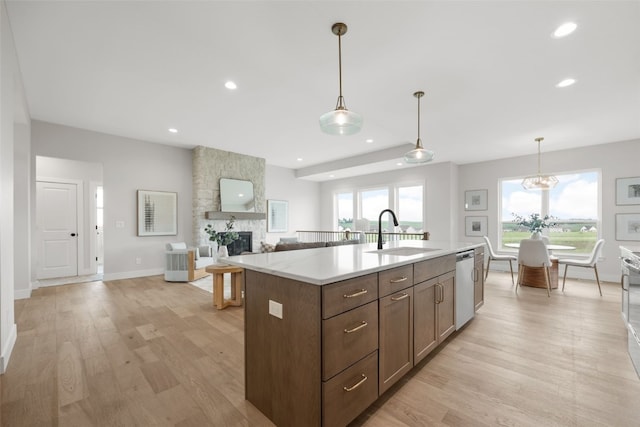 1519 Cardinal Dr, Fairfax, IA 52228 - kitchen featuring dishwasher, a fireplace, light countertops, light wood-style flooring, and a center island with sink
