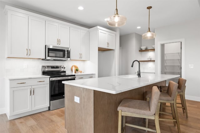 1519 Cardinal Dr, Fairfax, IA 52228 - kitchen with stainless steel appliances, light wood finished floors, decorative backsplash, white cabinetry, and recessed lighting